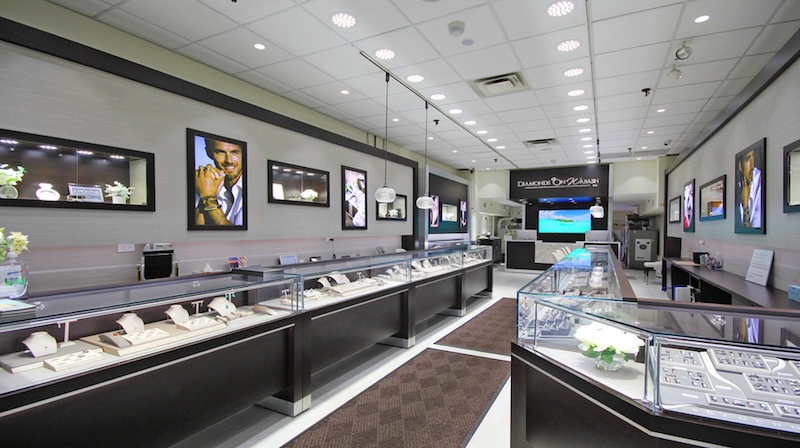 The interior of Diamonds On Wabash, featuring sleek display cases filled with a variety of diamond jewelry. The store is well-lit with modern decor and large images of jewelry and models on the walls.