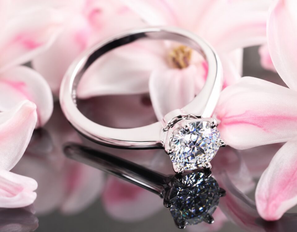 1.25 carat round diamond solitaire engagement ring surrounded by soft pink flowers.